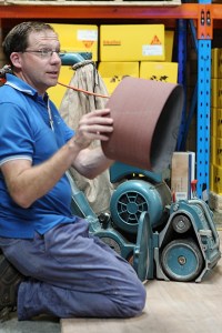 A person demonstrating a sanding tool while preparing to work on timber flooring, showcasing the equipment used in the coating process.